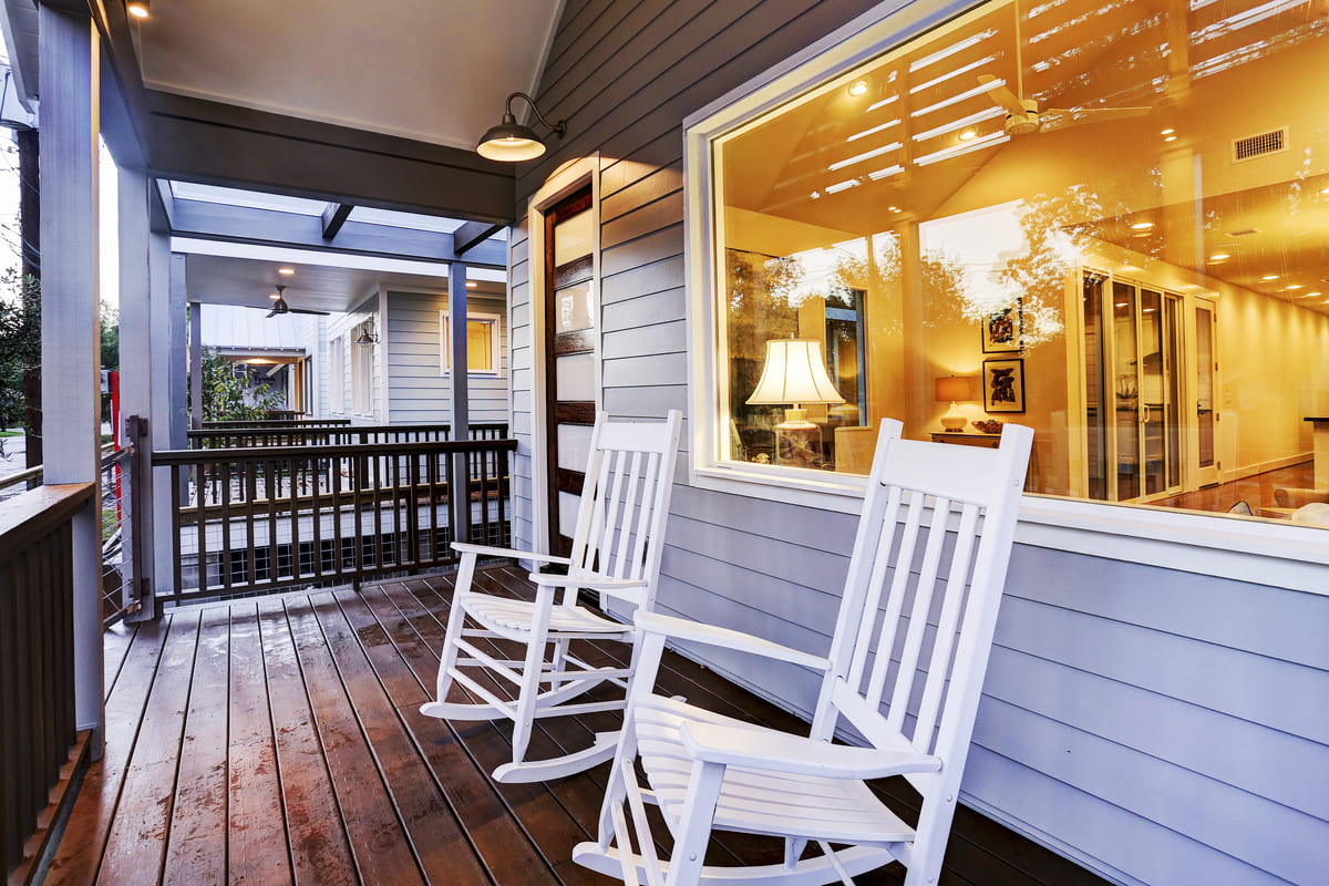 Custom Farmhouse Patio With Two White Patio Chairs, A Large  Energy Sufficient Window, & Light Blue Siding