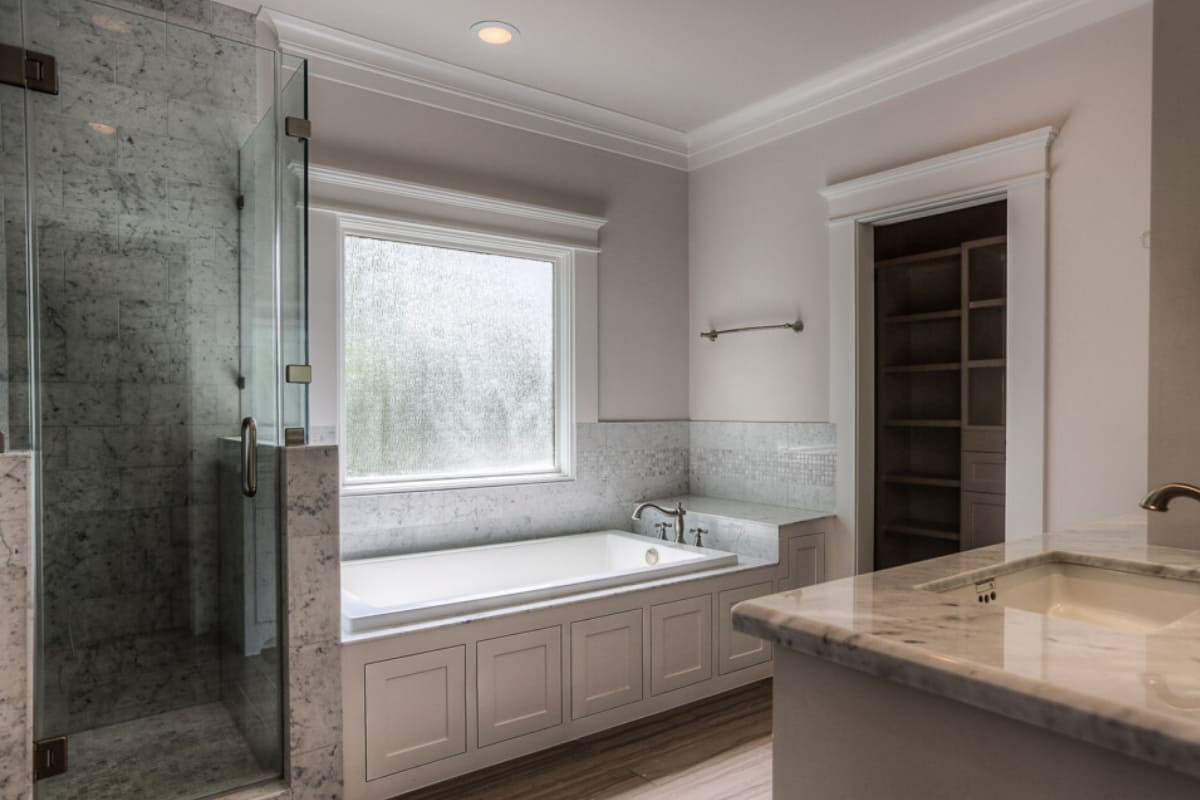 Custom bathtub with built-in storage in Houston bathroom by Southern Green