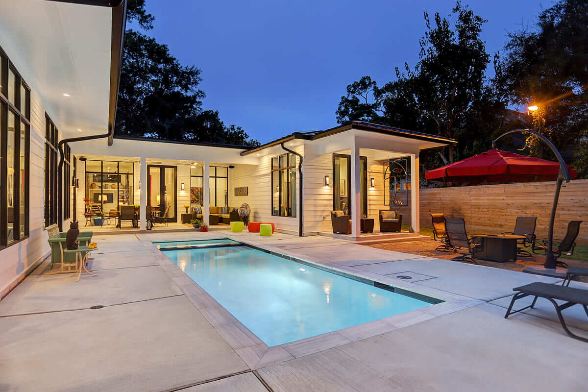 Outdoor inground pool with spacious surround and pool lounge chairs with umbrella hanging over