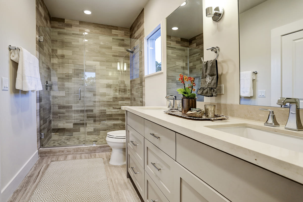 Custom Farmhouse Bathroom With A Walk In Shower, Double Vanity, And Grey Under Sink Storage Cabinets